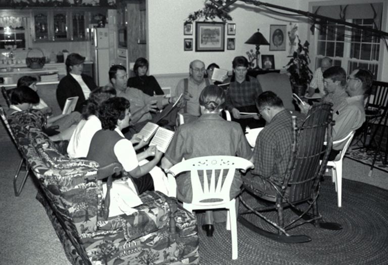 A group sings in a living room setting.